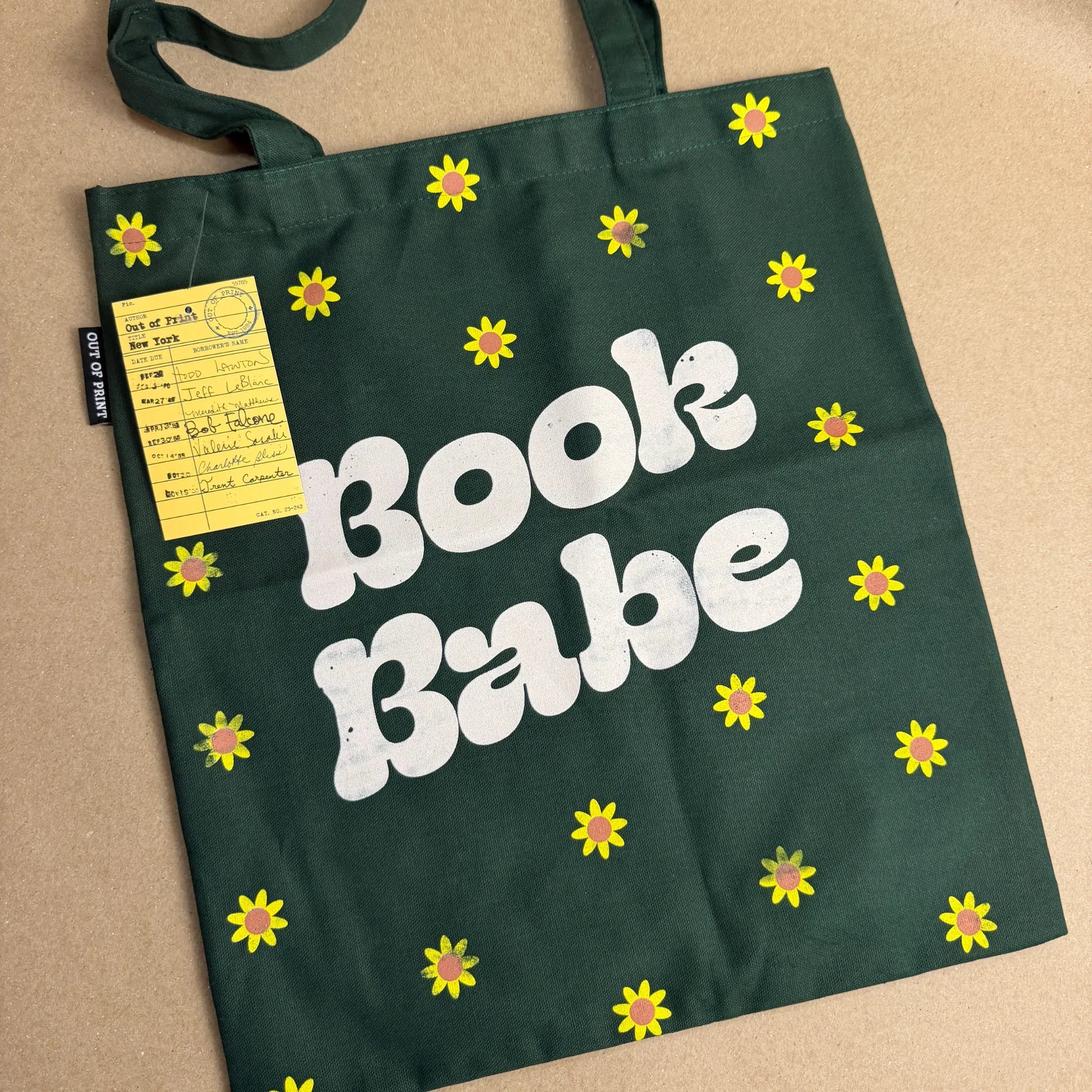 Green tote bag with 'Book Babe' text and floral patterns on a beige background