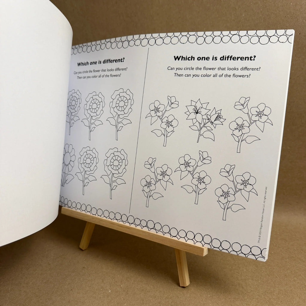 Educational book with coloring and activity pages on a wooden stand against a brown background