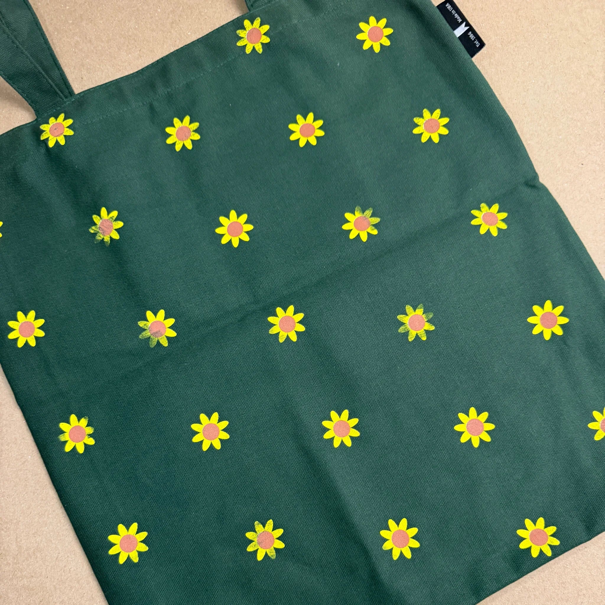 Green bag with yellow flower pattern on a beige surface
