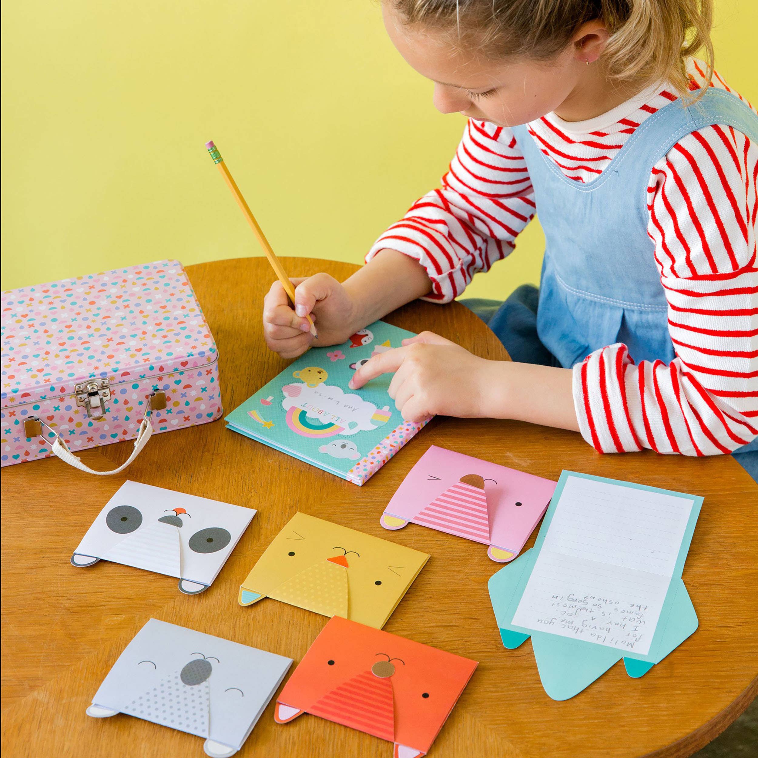 Child playing with colorful animal-shaped notebooks on a wooden table.