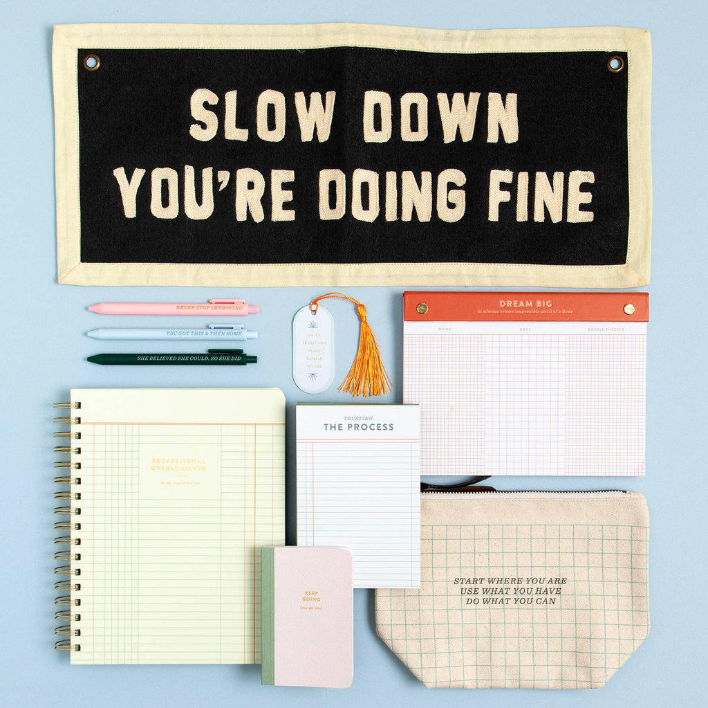 Stationery items including a notepad, pens, and a motivational sign on a light blue background