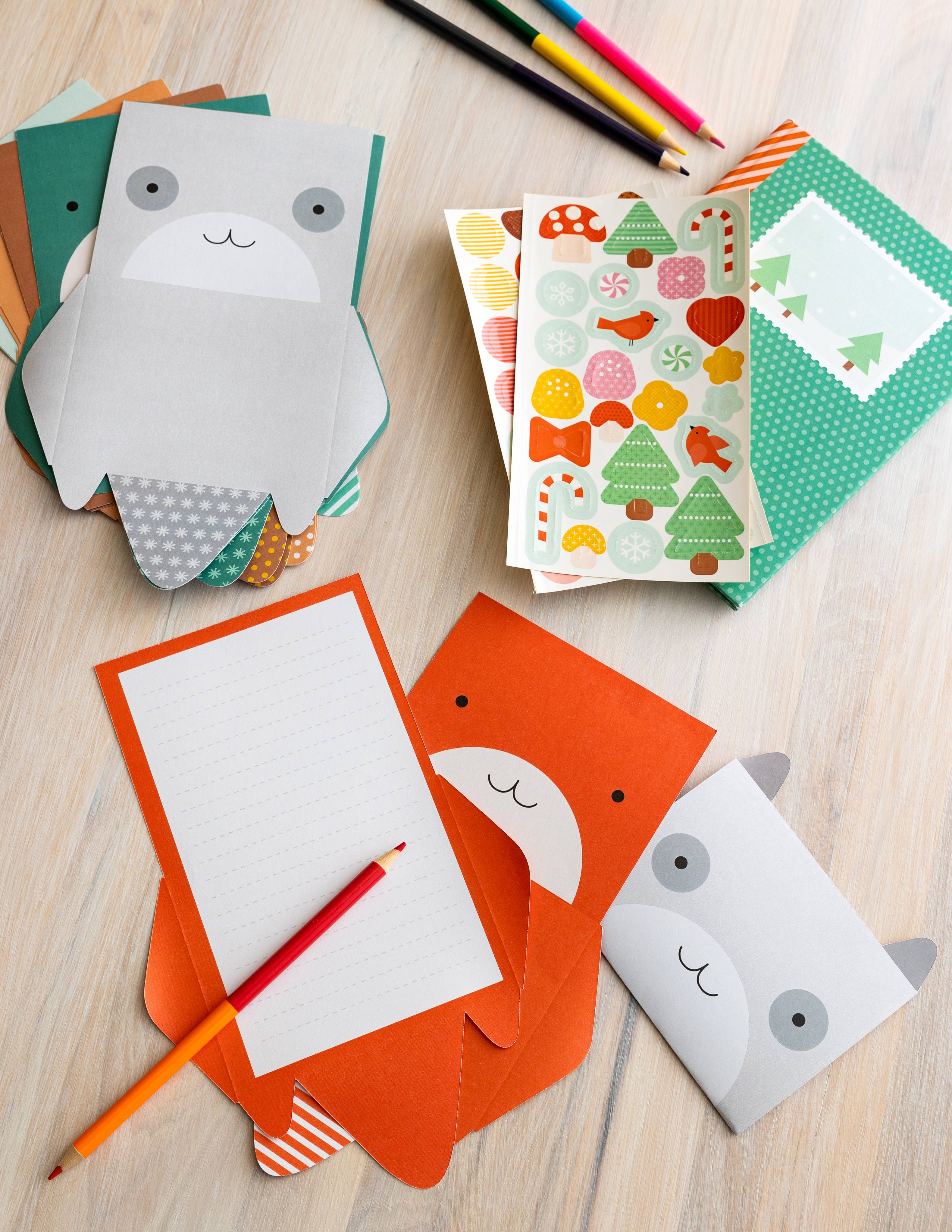 Colorful stationery items including envelopes and cards with animal designs on a wooden surface.