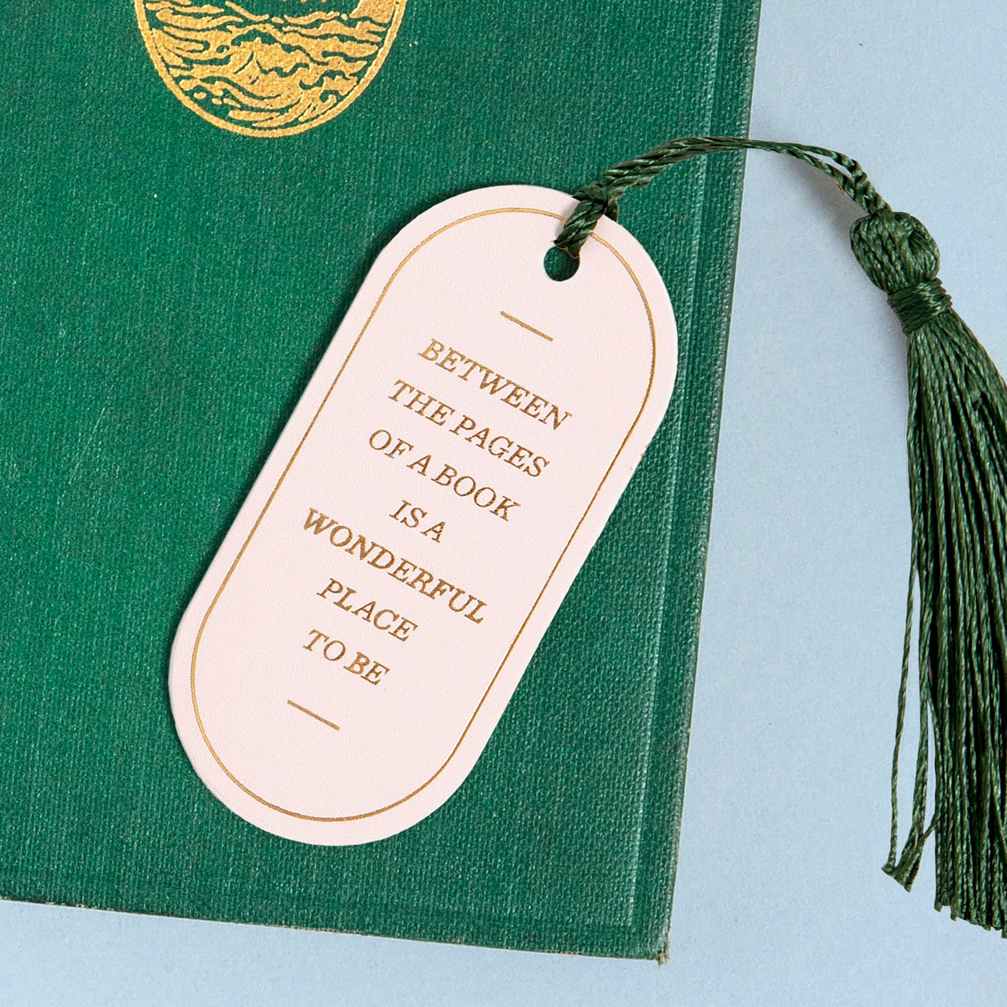 Green book with a decorative bookmark on a light blue background