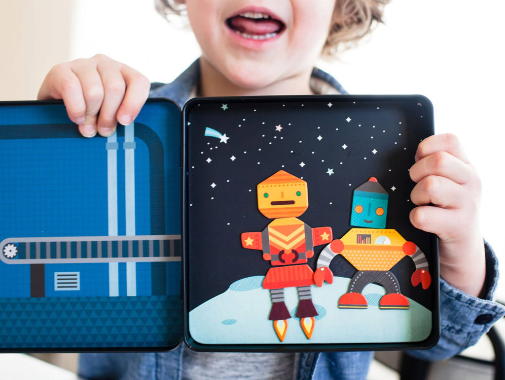 Child holding open magnetic playset with colorful robot figures on space-themed background, perfect for imaginative play.