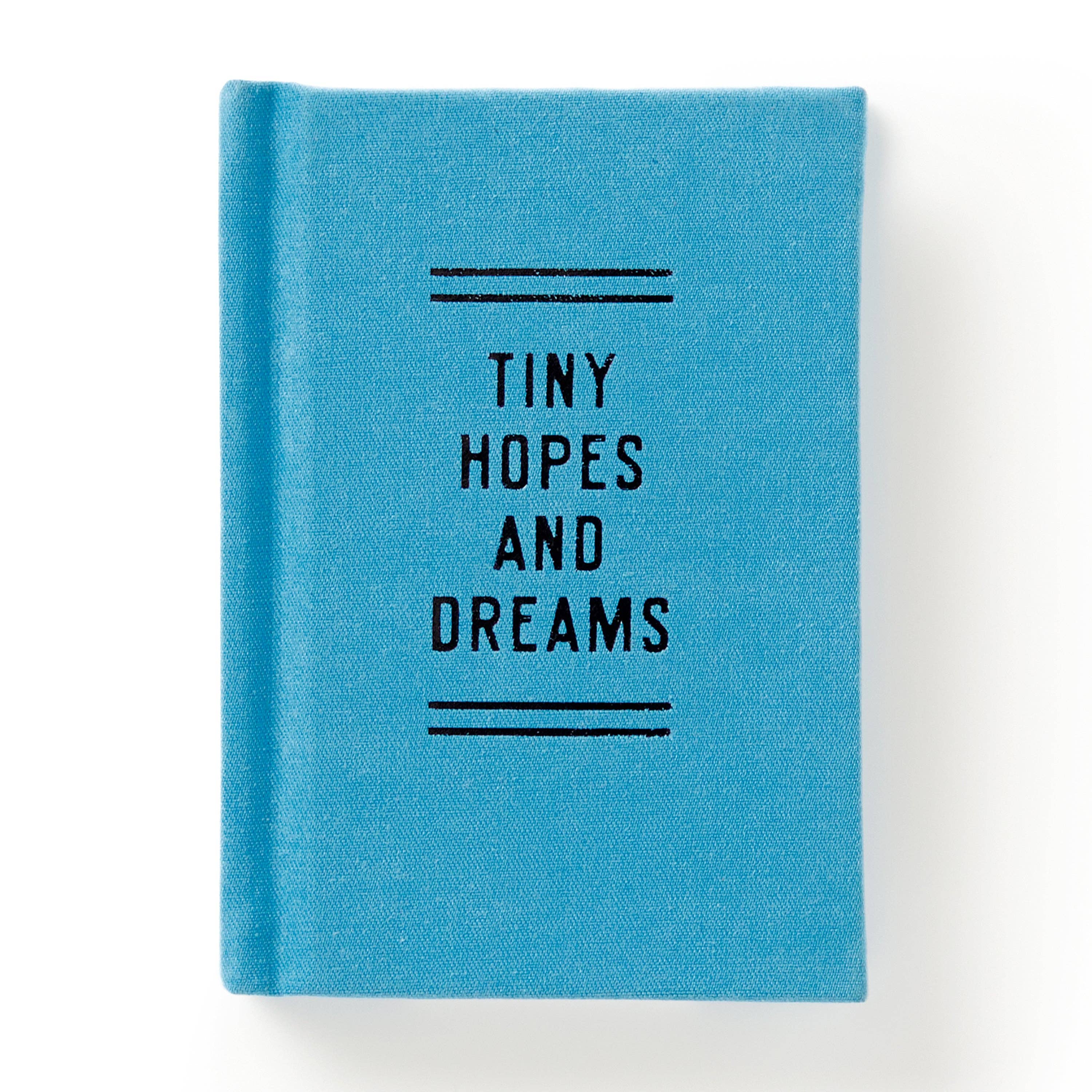 Blue fabric journal with 'Tiny Hopes and Dreams' text, ideal for cozy reads and intentional play.