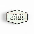 Hexagonal enamel pin with 'I closed my book to be here' text on lined paper design, perfect for book lovers and cozy reads.