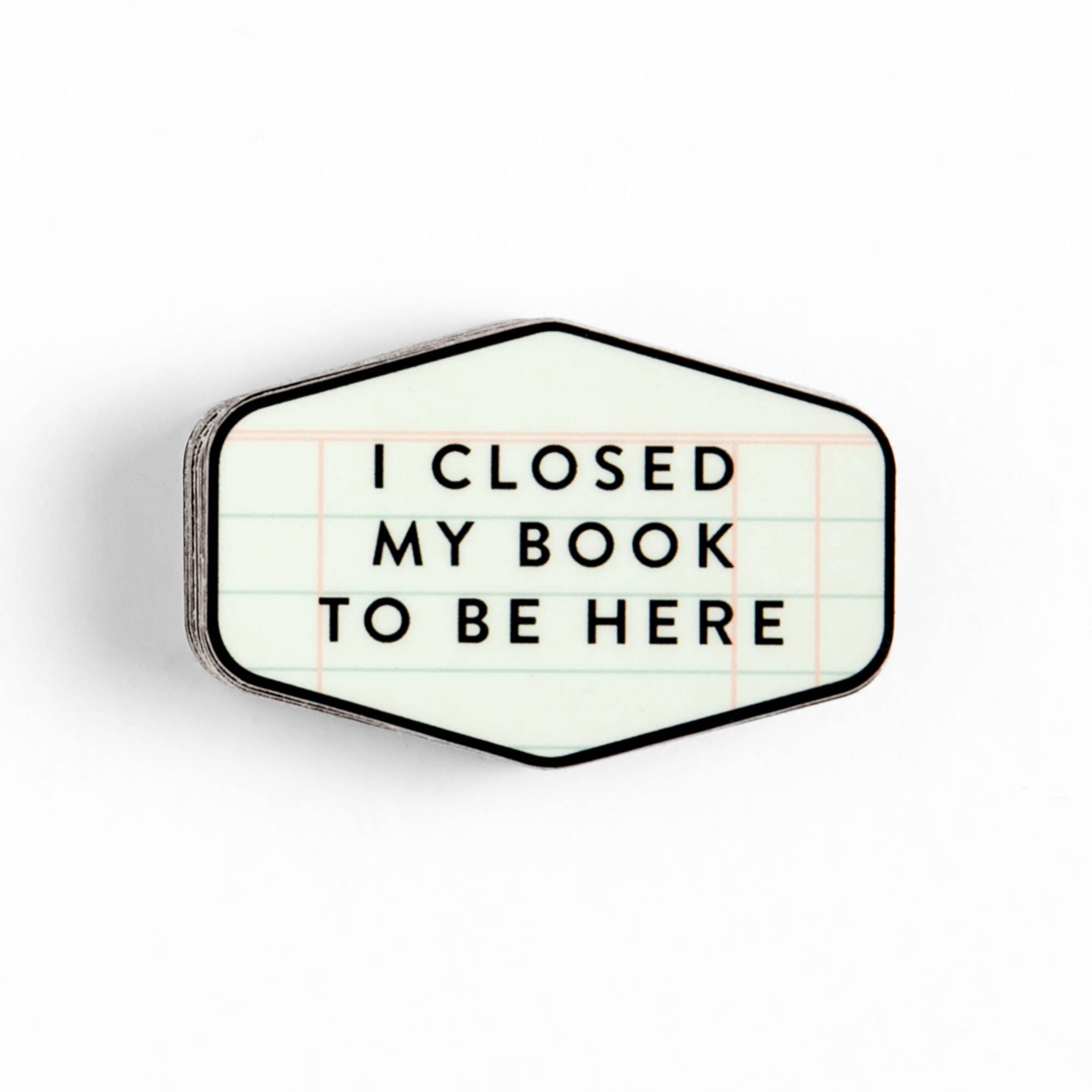 Hexagonal enamel pin with 'I closed my book to be here' text on lined paper design, perfect for book lovers and cozy reads.